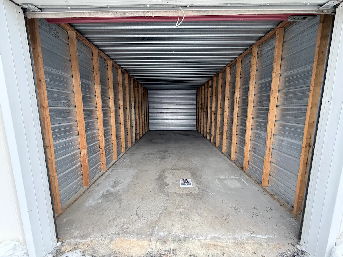 Interior of a 10x25 residential storage unit in Scranton with wooden shelving frame and horizontal metal storage slats, concrete floor, and clear space for personal items